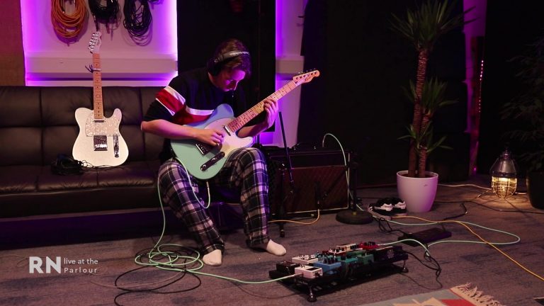 man playing guitar with pedals in studio